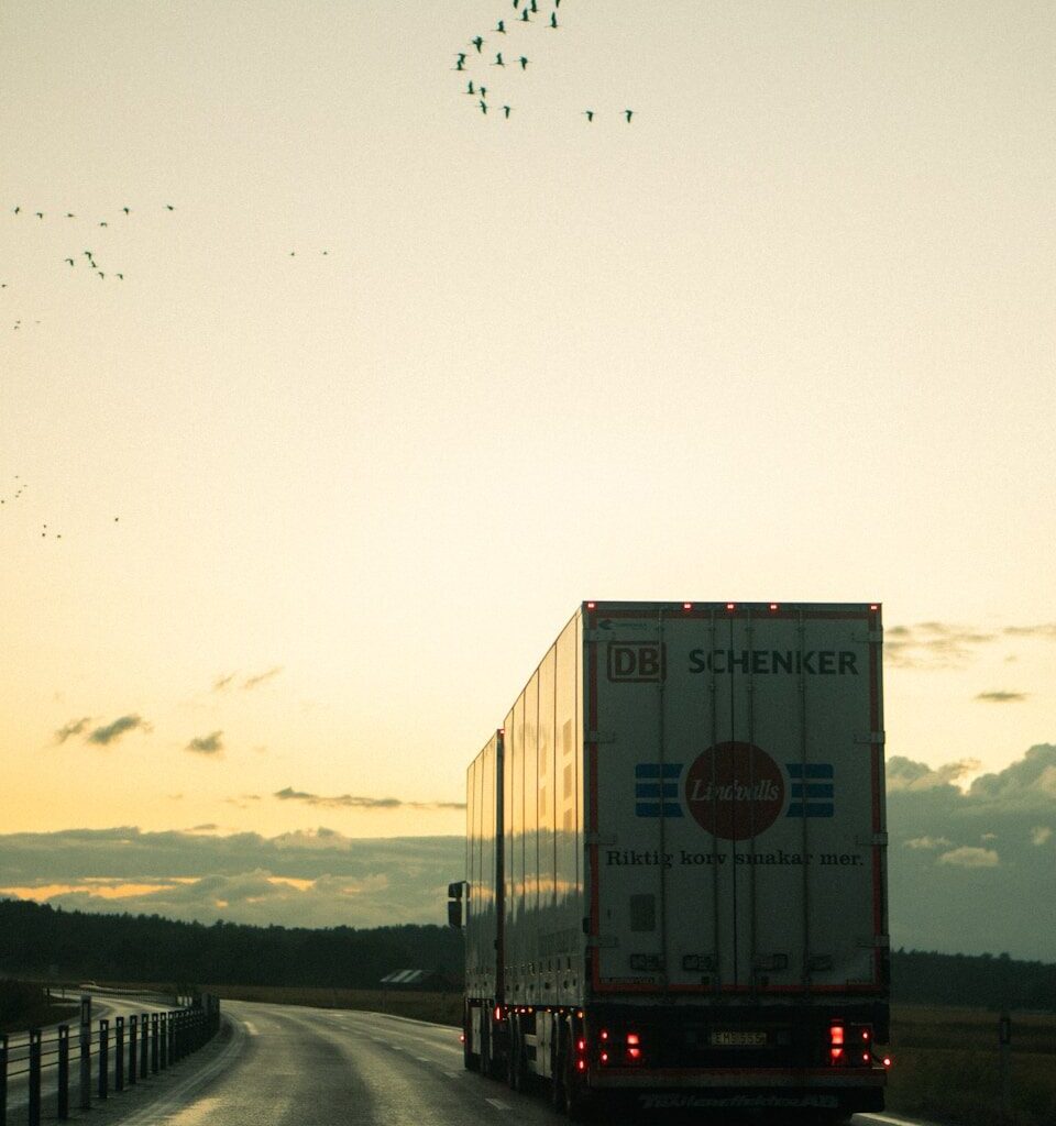 a semi truck driving down a road at sunset